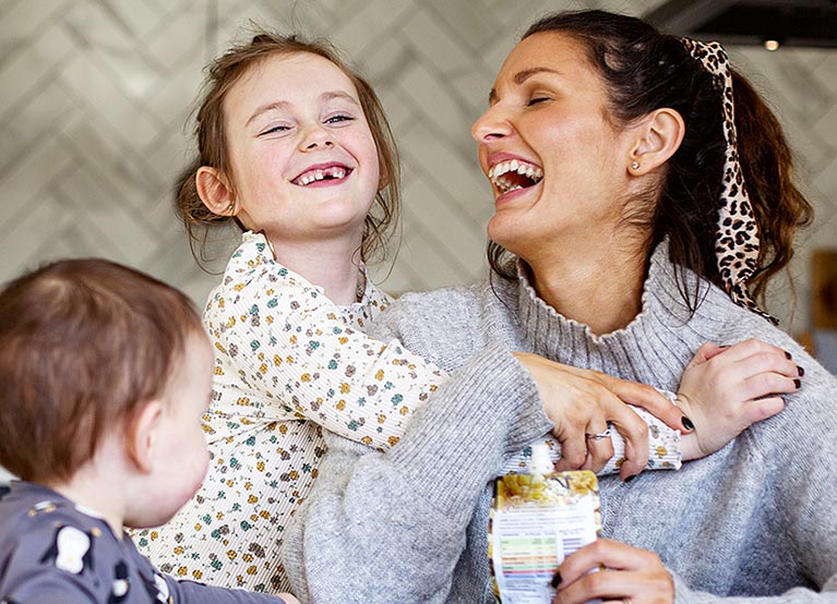 mom smiling and laughing with two young children