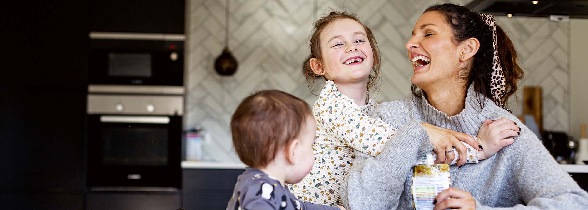 mom smiling and laughing with two young children