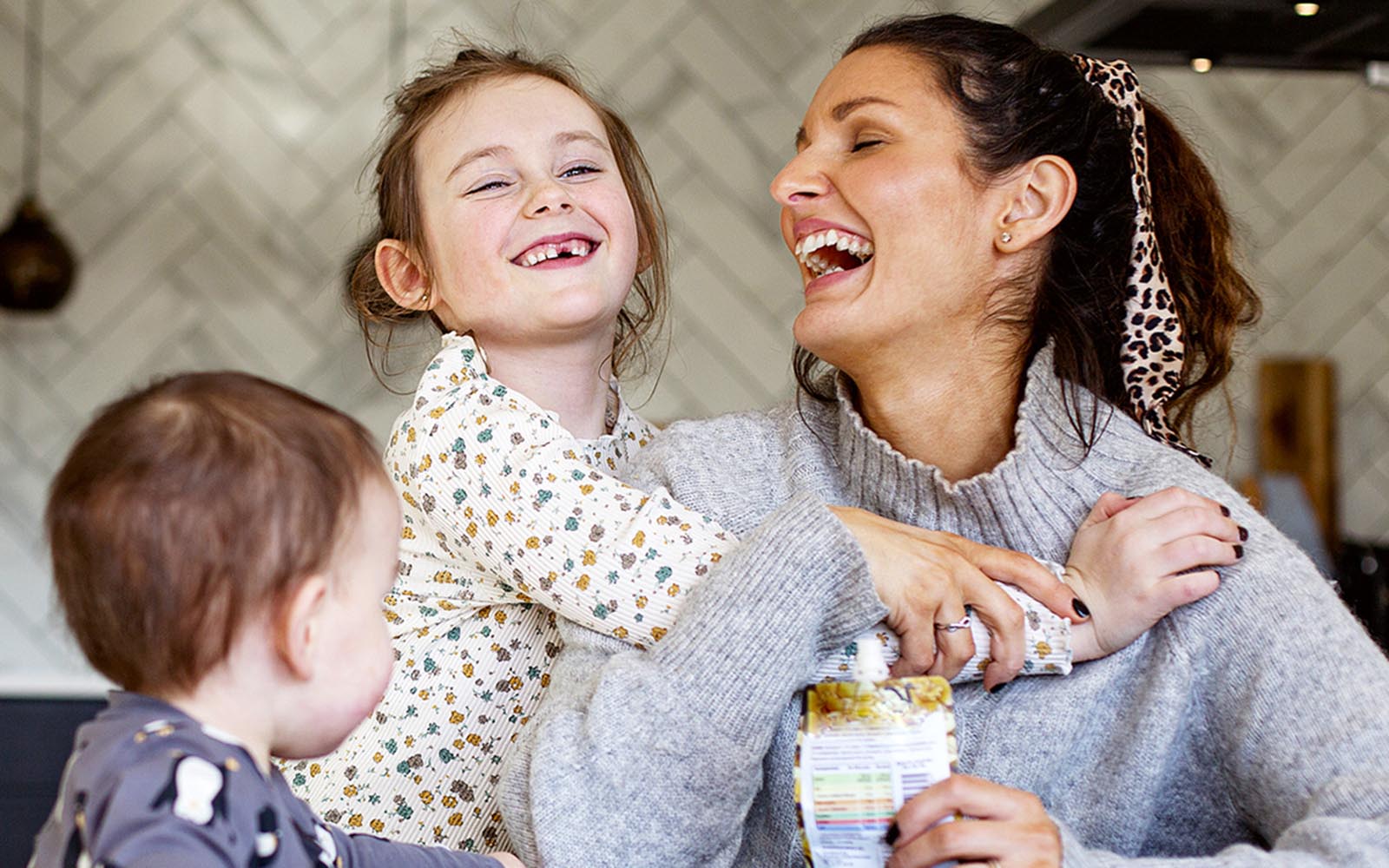 mom smiling and laughing with two young children